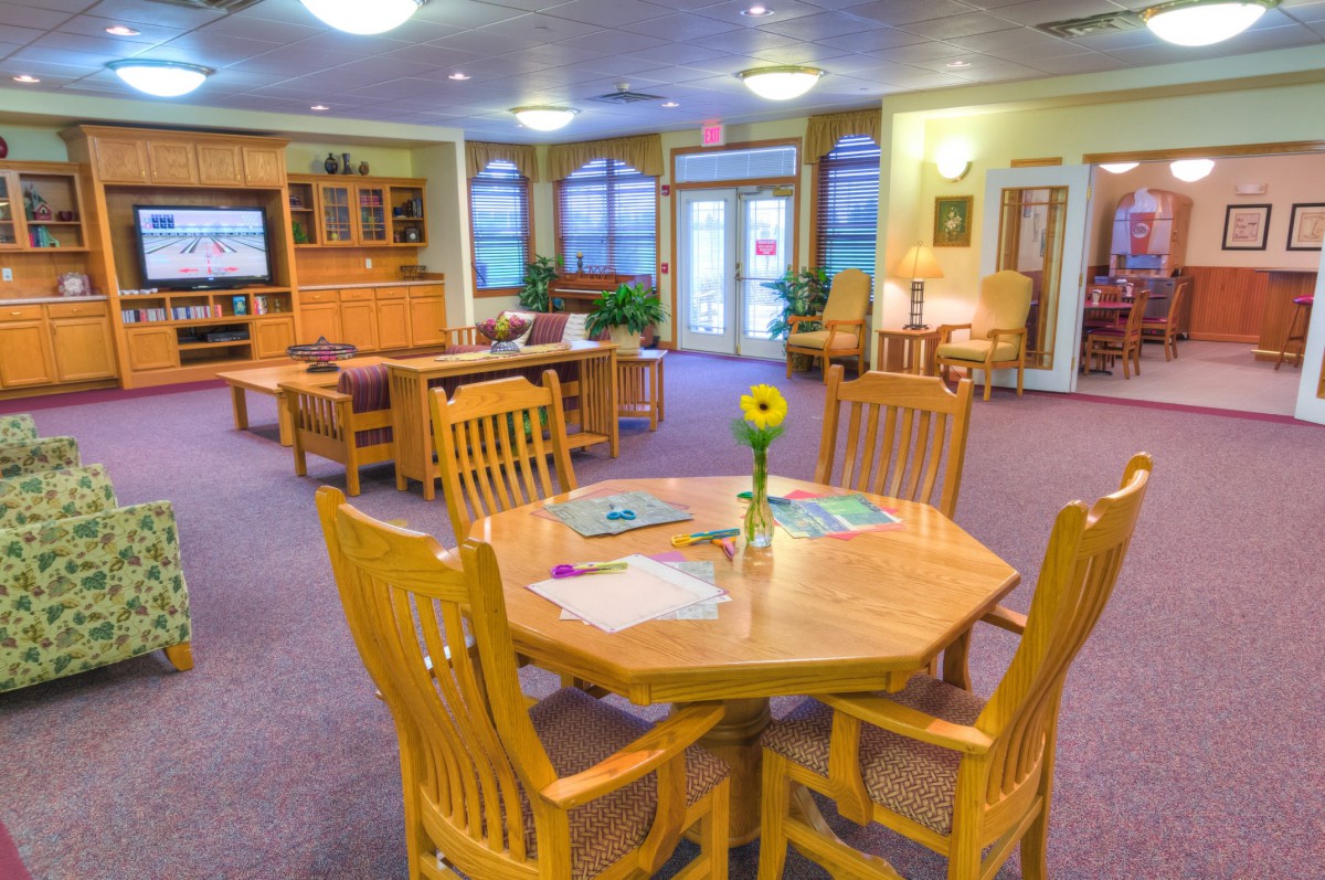 A cozy community room with wooden tables and chairs arranged for social gatherings.