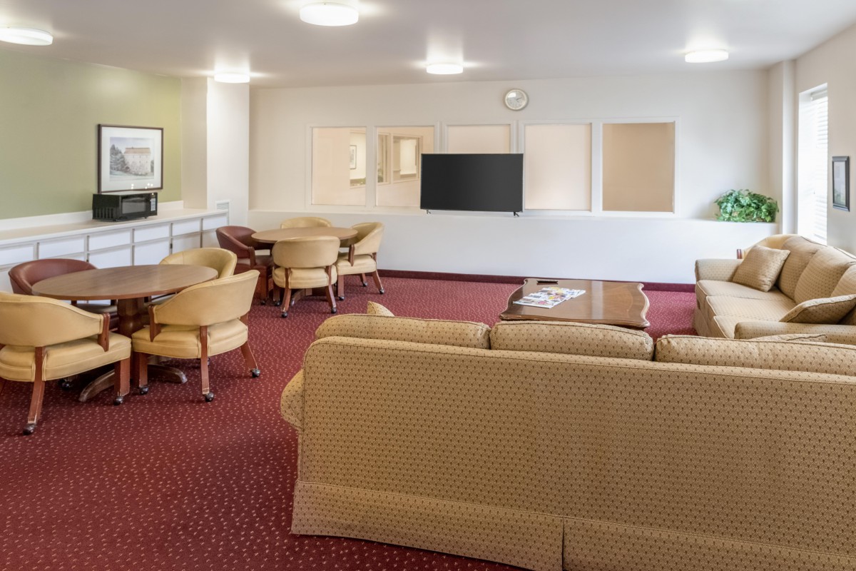 A spacious living area with sofas, chairs, and a television.