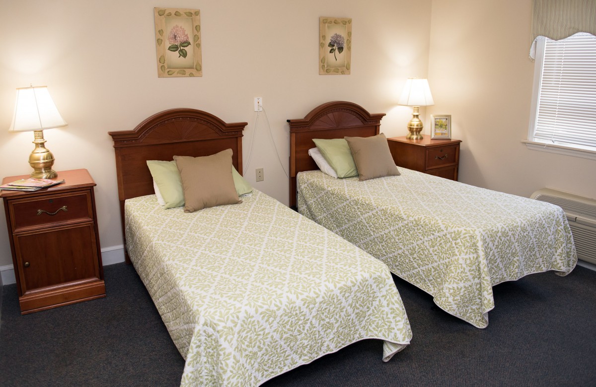 A cozy bedroom with two twin beds, decorative pillows, and matching wall art.