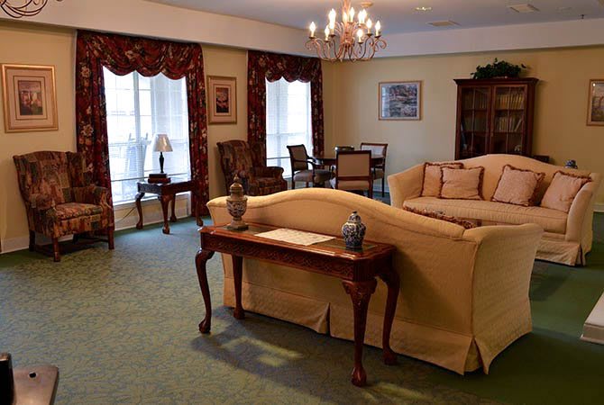 A classic living room with elegant furnishings, featuring a sofa, wooden table, and chandelier.