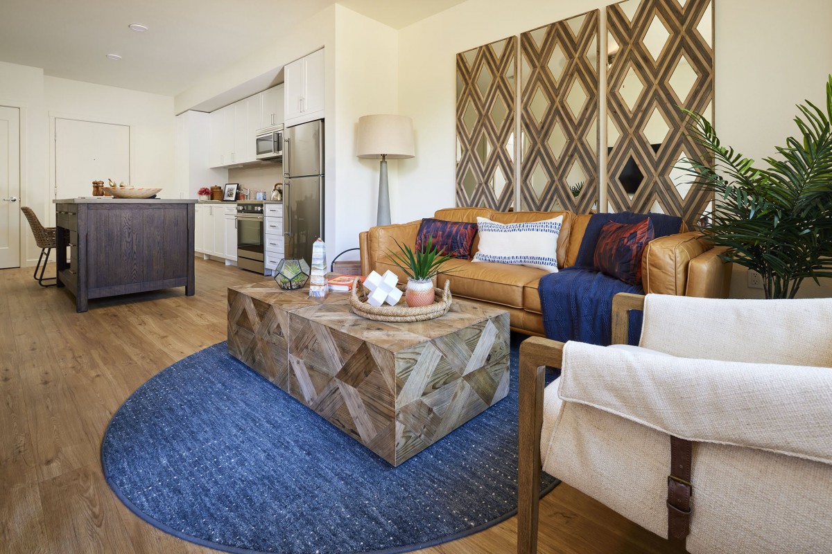 A modern living room with a cozy atmosphere, featuring a wooden coffee table, a blue round rug, and comfortable seating.