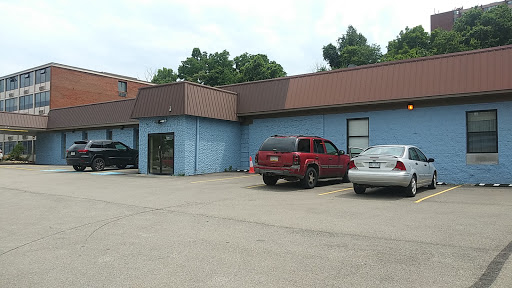 A commercial building with a blue exterior and parked vehicles in the lot.