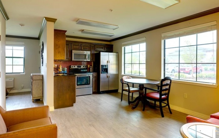 A cozy kitchen and dining area featuring modern appliances, a table with chairs, and large windows.