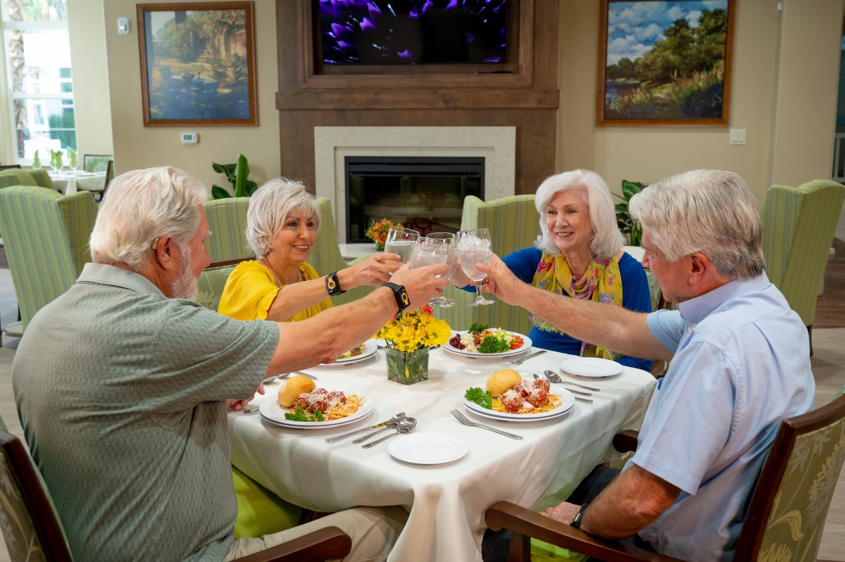 A group of seniors toasting at a dining table, enjoying a meal together.