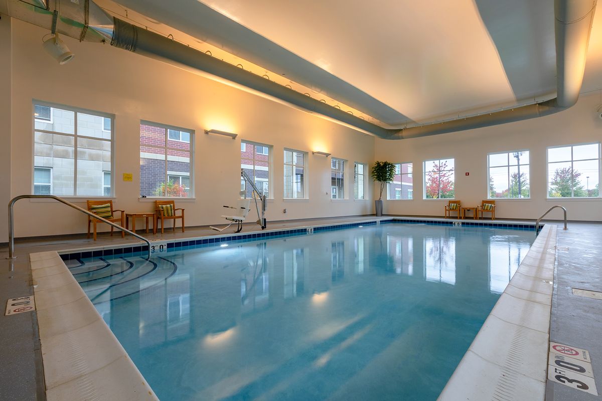 An inviting indoor swimming pool area with ample natural light and comfortable seating.
