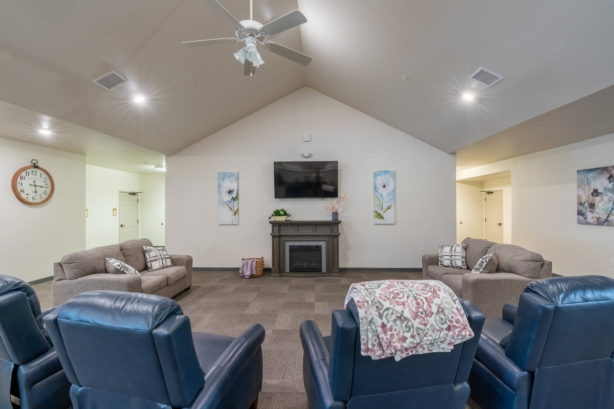 A cozy living room featuring comfortable seating, a TV mounted above a fireplace, and decorative wall art.