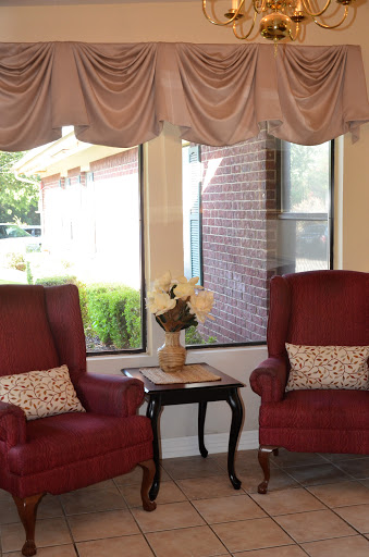 A cozy corner of a living room featuring two red chairs and a small table with a flower arrangement.