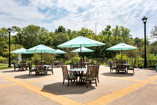 A beautifully arranged outdoor seating area featuring tables with teal umbrellas surrounded by lush greenery.