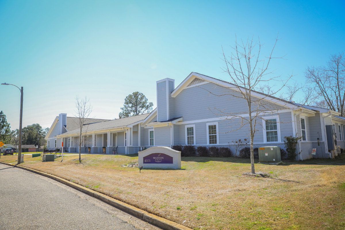 A single-story building with a light gray exterior under a clear blue sky.