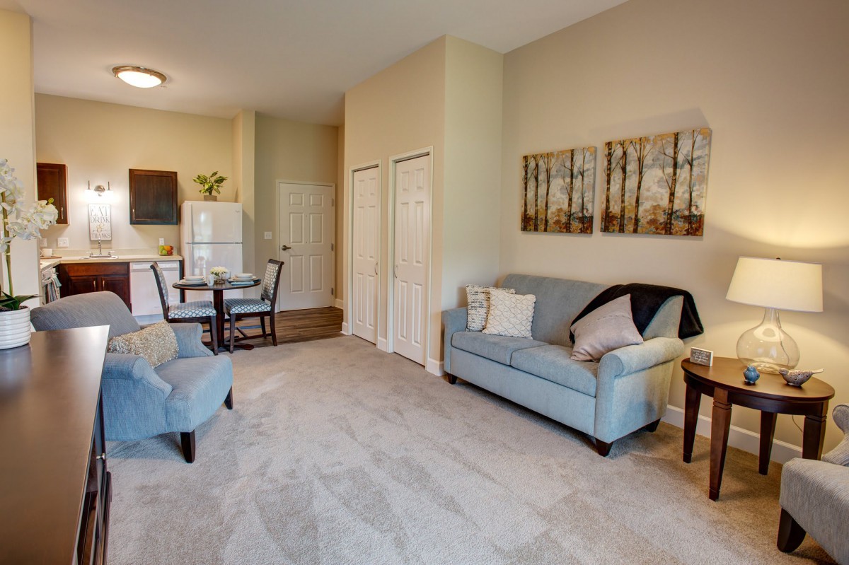 A cozy living space featuring a sofa, chair, and dining area with a view into the kitchen.