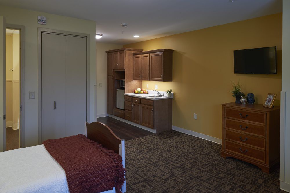 A hotel room featuring a cozy bedroom and a small kitchenette area.