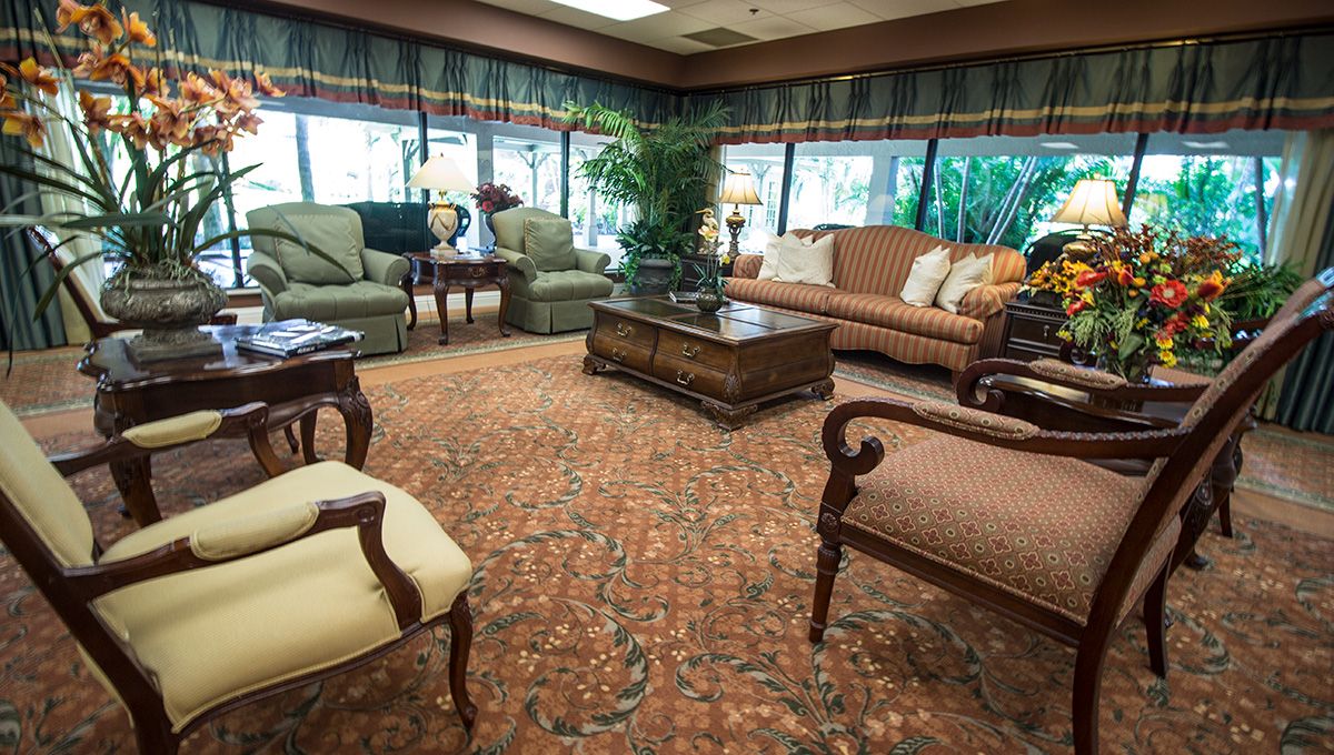 A traditionally styled living room with comfortable sofas, a coffee table, and lush greenery.