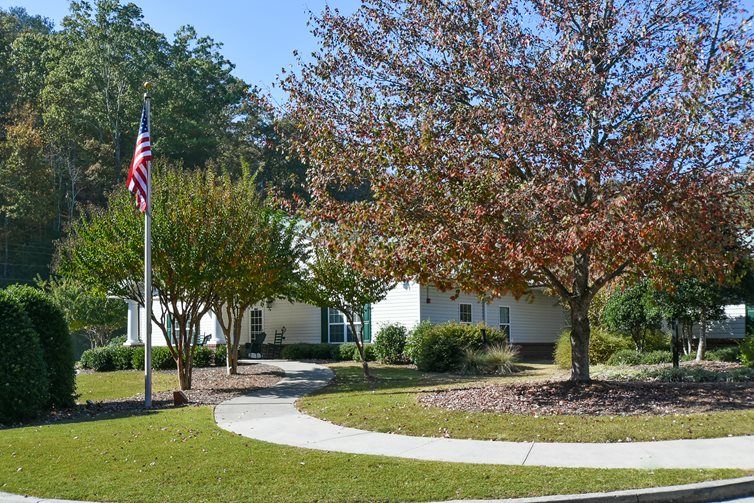 A well-maintained building surrounded by trees and a manicured lawn, with an American flag flying nearby.