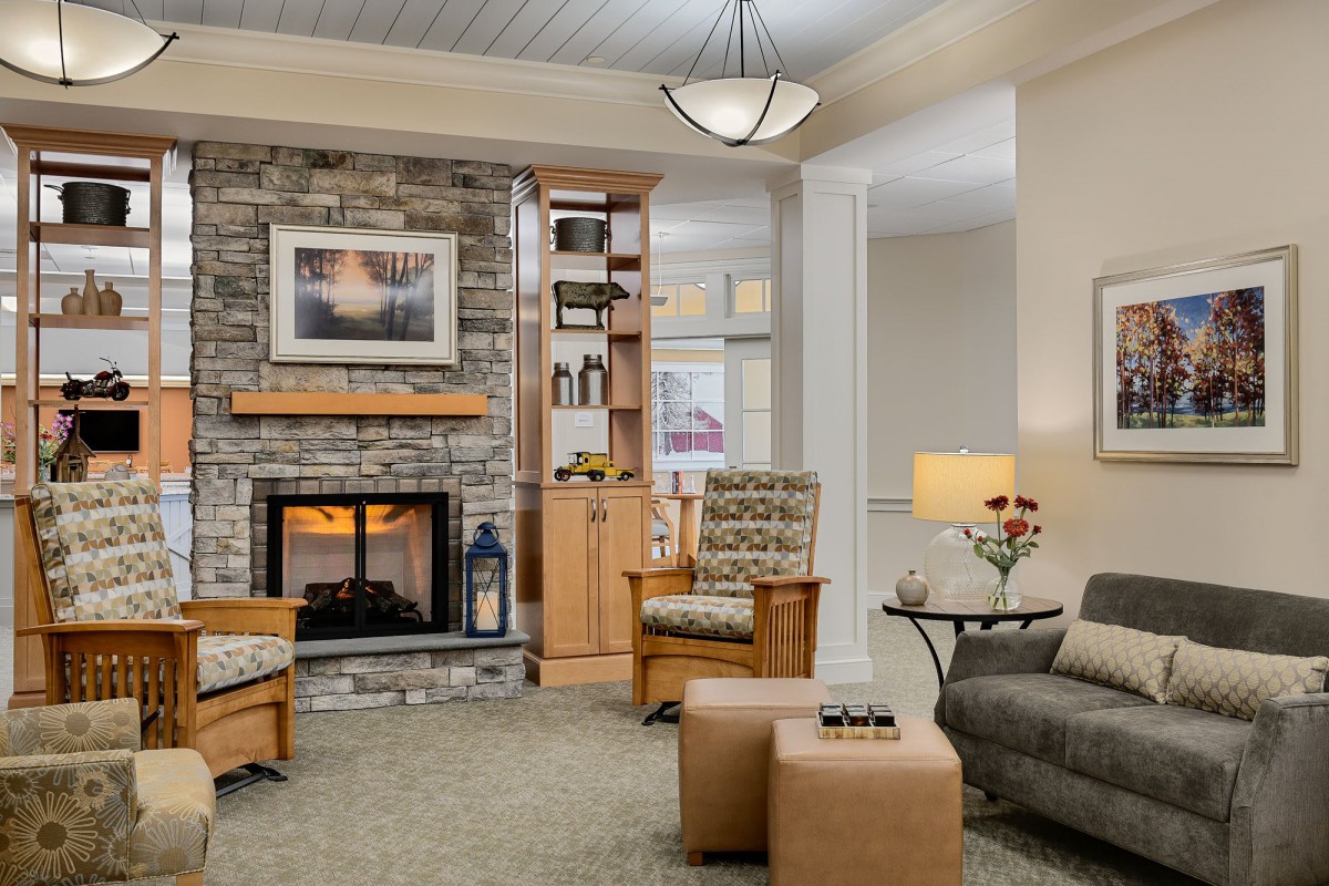 A cozy living room with a stone fireplace, modern furniture, and decorative artwork.