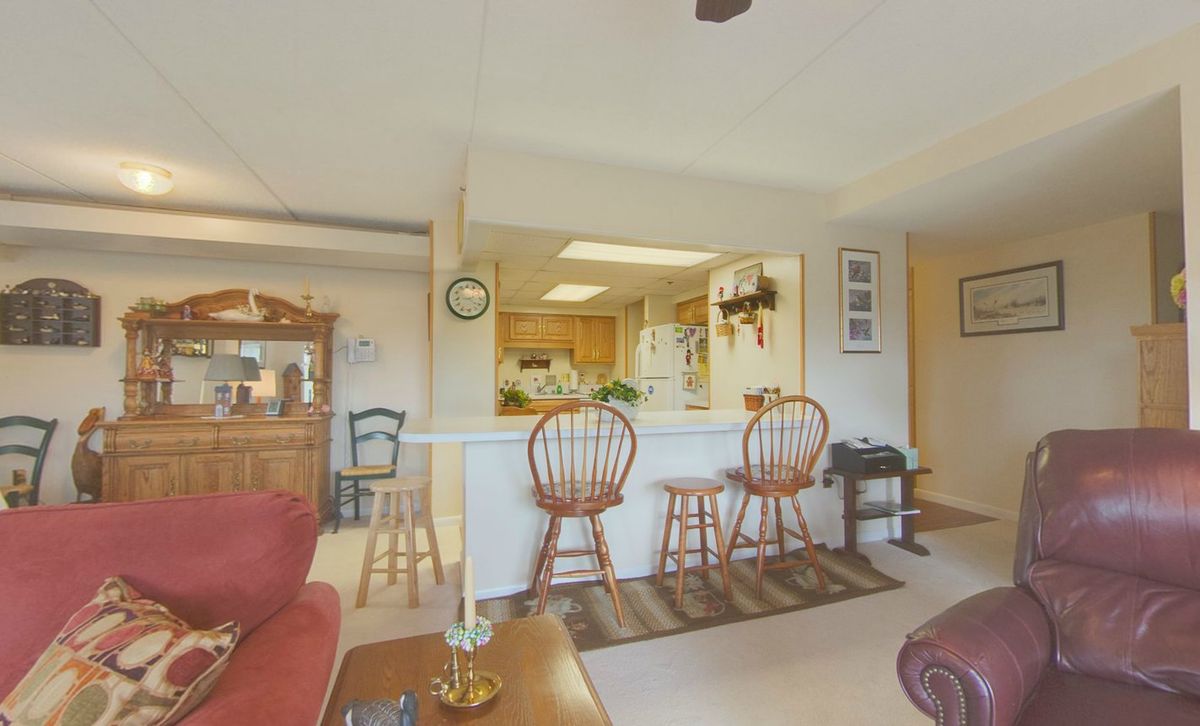 A cozy open-space living area with a view into the kitchen and bar stools at the counter.