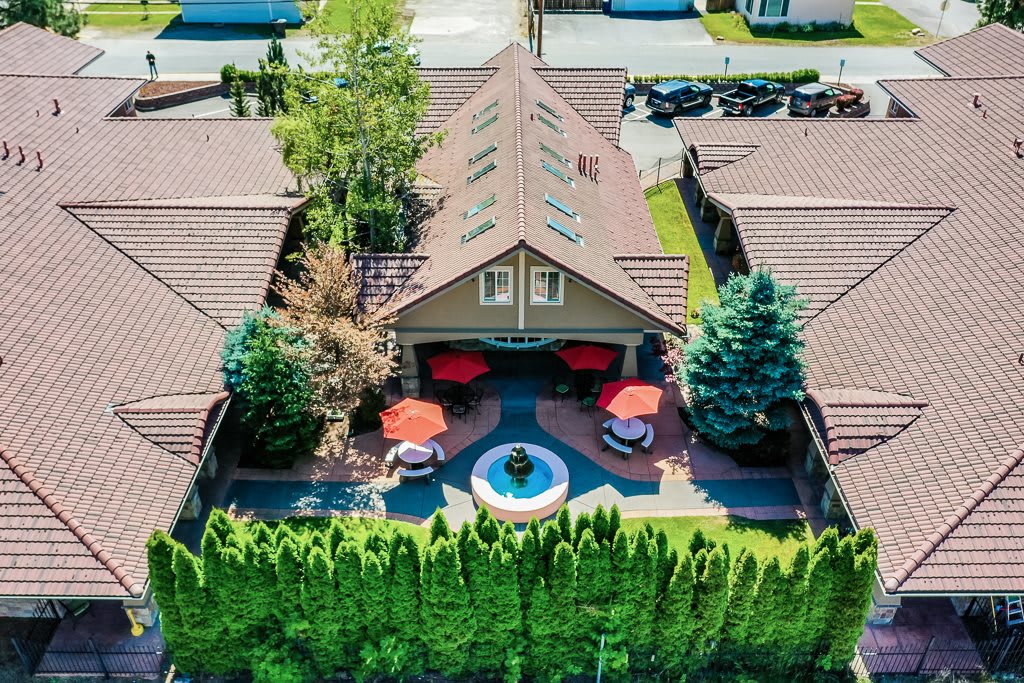 Aerial view of a house with a landscaped backyard featuring a fountain and patio seating.