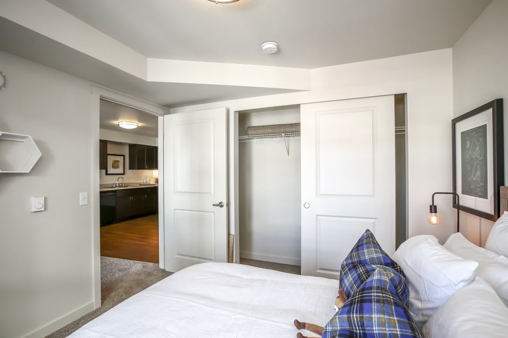 A bedroom with an open closet door, featuring a bed and pillows.