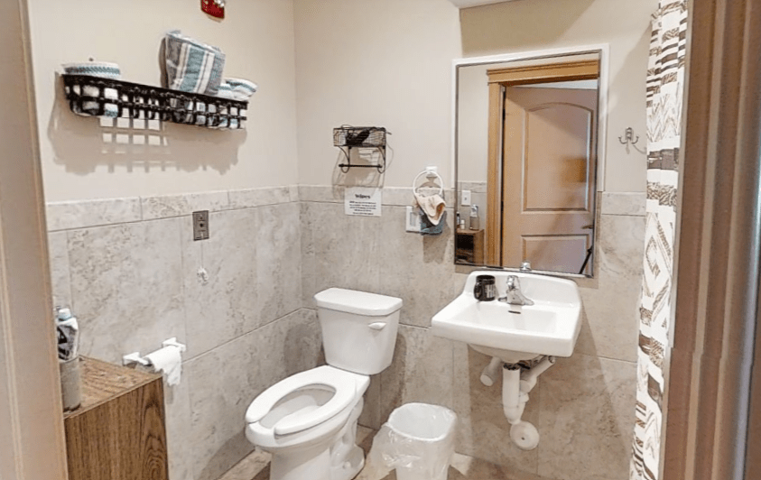 A neatly organized bathroom featuring a toilet, sink, and mirror.