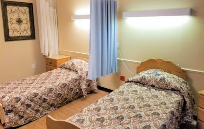 A simple hospital room with two beds separated by a curtain.