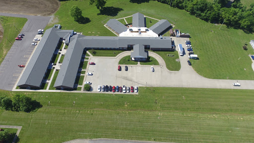 An aerial view of a large facility with a parking lot and surrounding green space.