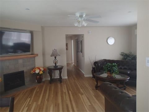 A cozy living room with a sofa set, fireplace, and wooden flooring.