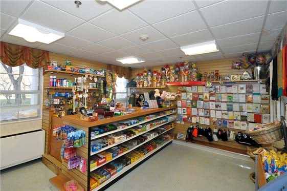 The image shows the interior of a small retail store with various products displayed on shelves.