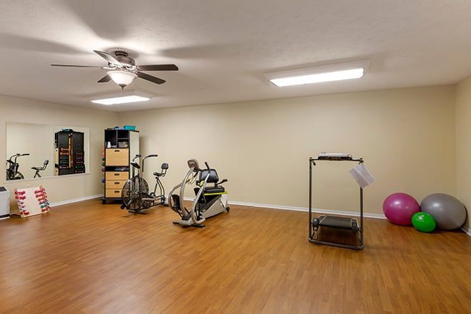 A home gym equipped with a treadmill, stationary bike, and other fitness equipment on a wooden floor.