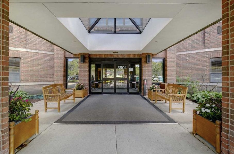 Entrance to a modern building with glass doors and wooden benches.