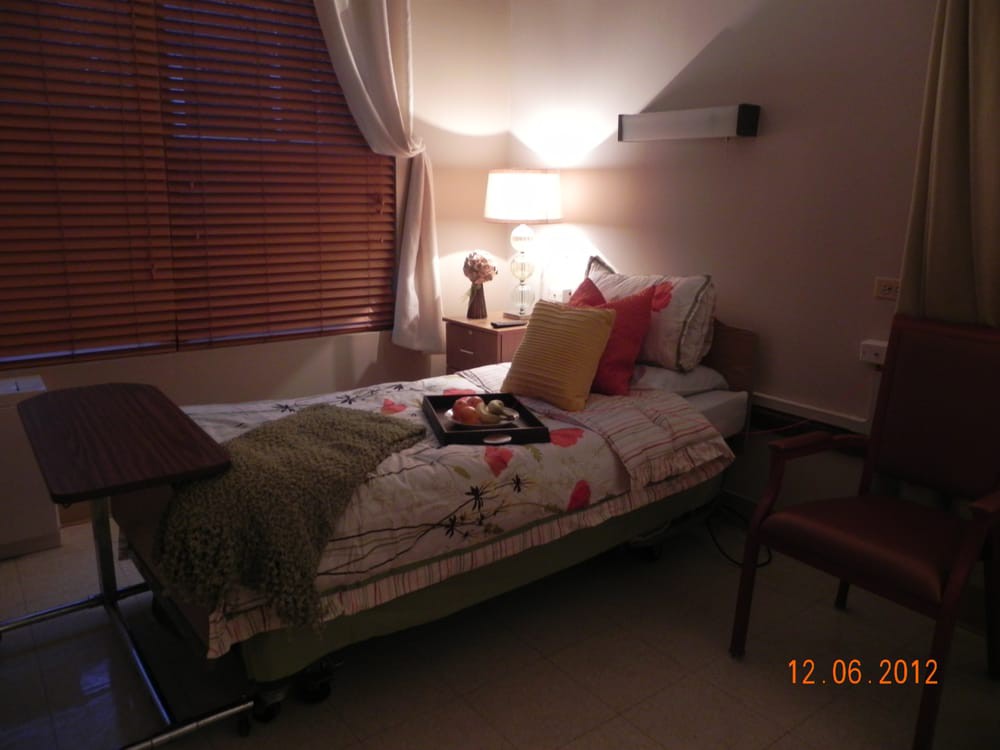 A cozy bedroom with a neatly made bed, soft lighting from a lamp, and comfortable pillows.