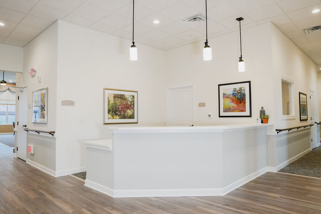 A modern reception area featuring bright walls, pendant lighting, and contemporary artwork on the walls.