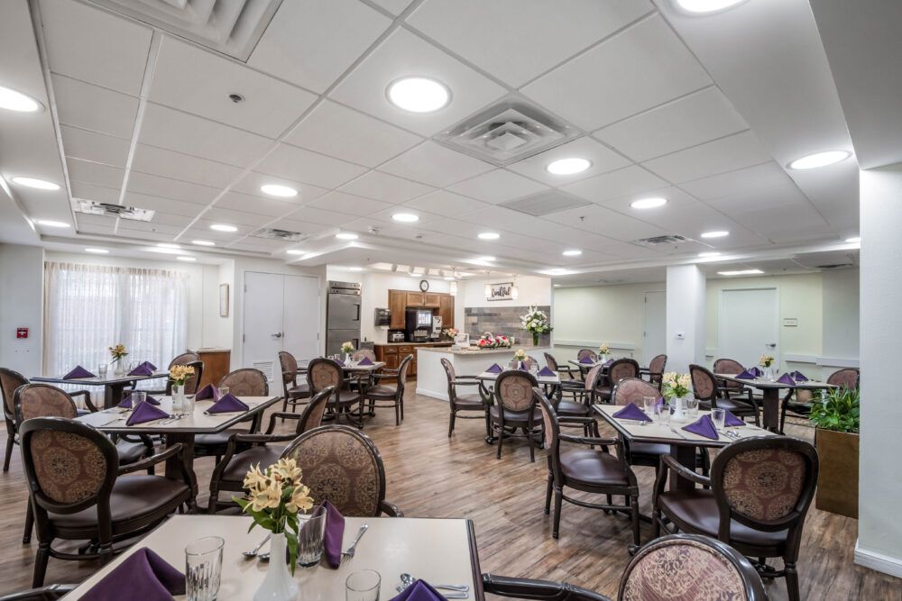 A cozy dining area with neatly arranged tables and chairs, adorned with flowers and napkins.