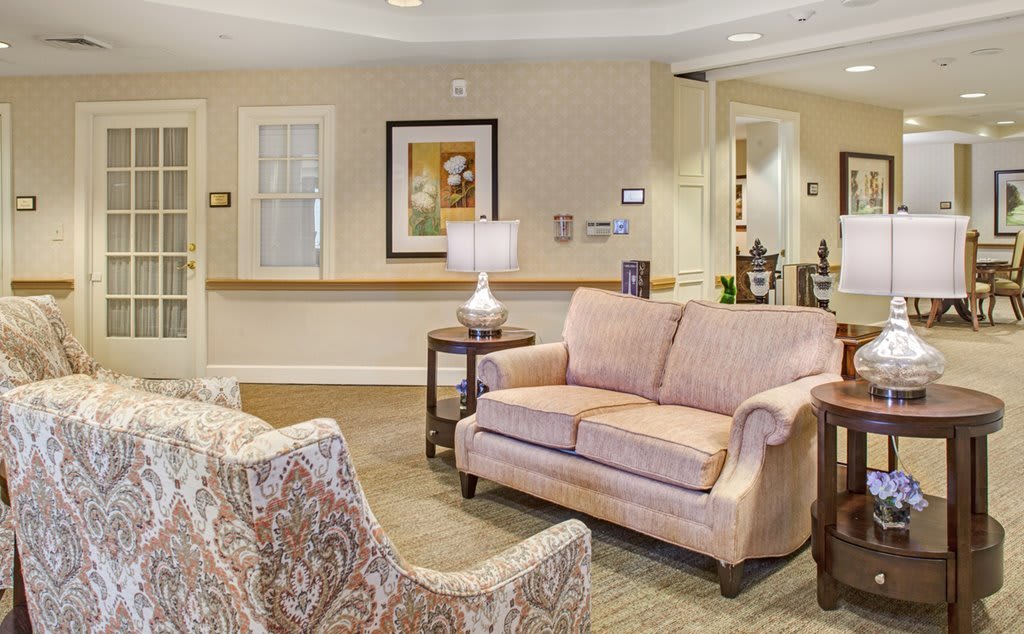 A cozy living room with a couch, armchairs, and a lamp in a warmly decorated space.