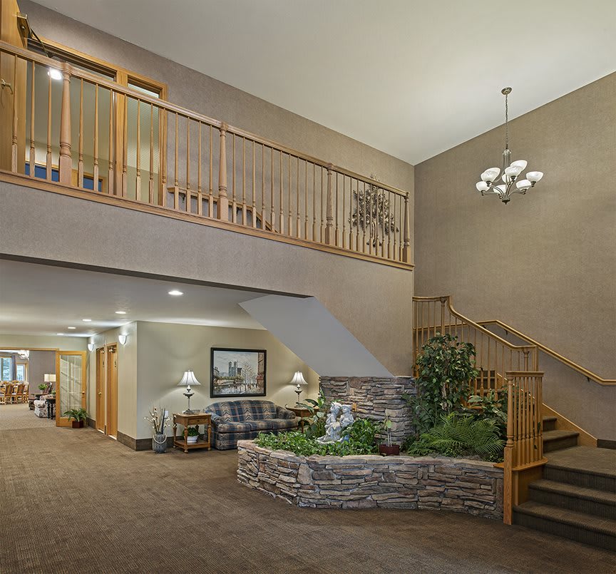 A spacious lobby area with a staircase, indoor garden, and chandelier.