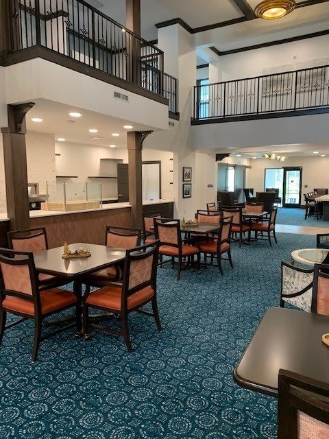A spacious dining area with multiple tables and chairs, featuring modern architecture and lighting.