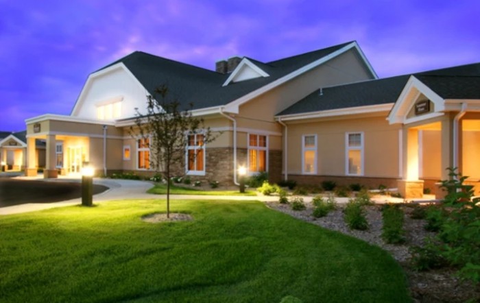 A well-lit house with a landscaped yard during the evening.