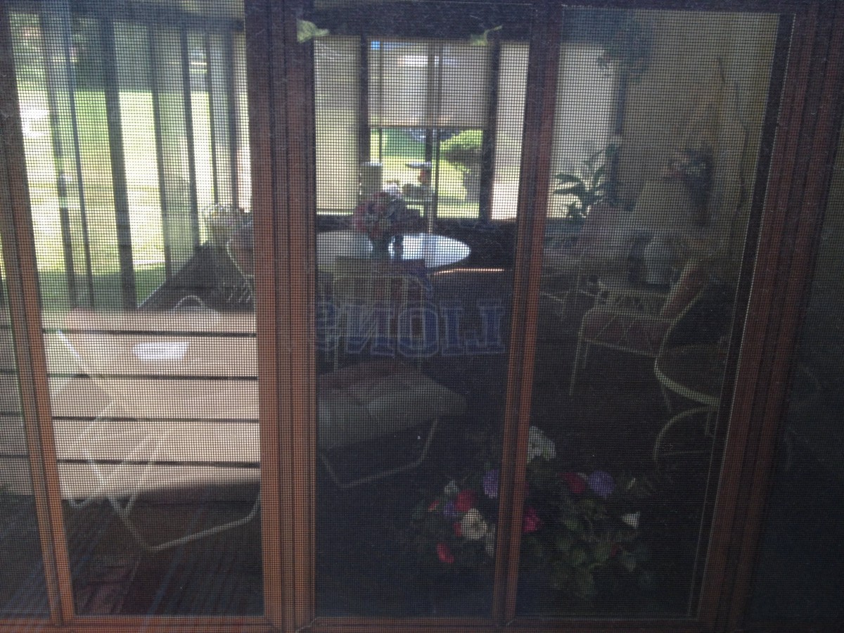 A cozy indoor space with wicker furniture and large windows showcasing a garden view.