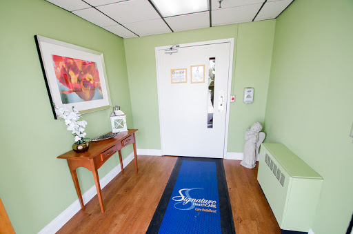 A welcoming foyer featuring green walls, wooden furniture, and decorative elements.