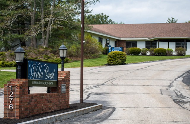 A nursing home with a prominent sign and well-maintained landscaping.