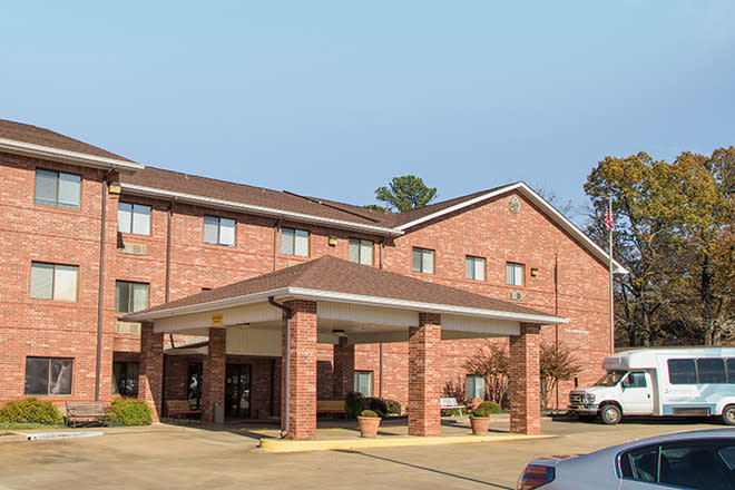 A brick exterior hotel with a covered entrance and landscaped surroundings.