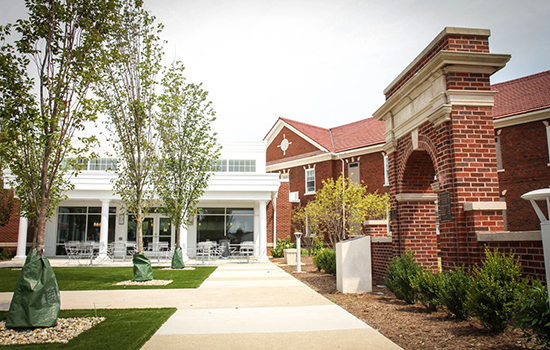 A modern brick building with a landscaped entrance and walkway.