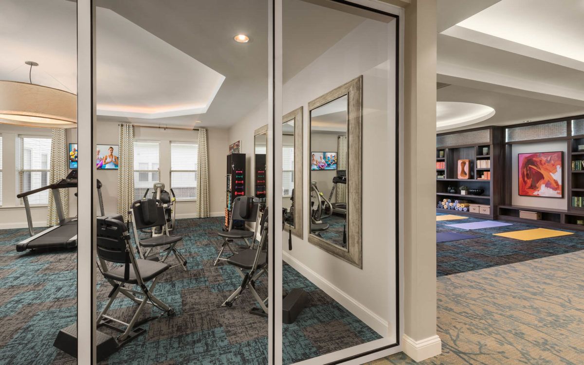 A modern gym with exercise equipment and mirrored walls.