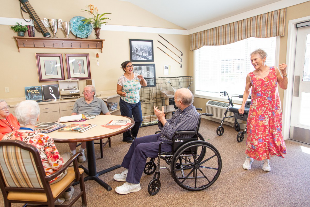 A group of seniors interacting in a cozy nursing home setting.
