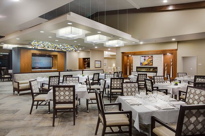 Elegant restaurant interior with neatly arranged tables and chairs under modern lighting.