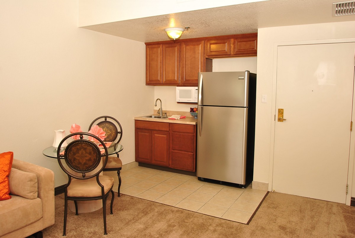 Compact kitchen and dining area with wooden cabinets and a stainless steel refrigerator.