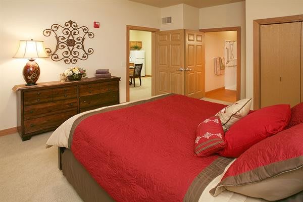 A cozy bedroom with a red comforter and stylish decor.