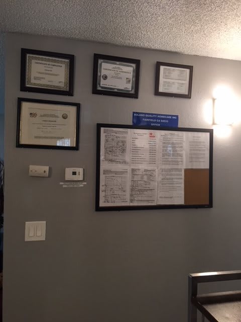 A wall display of framed certificates and documents in an office setting.