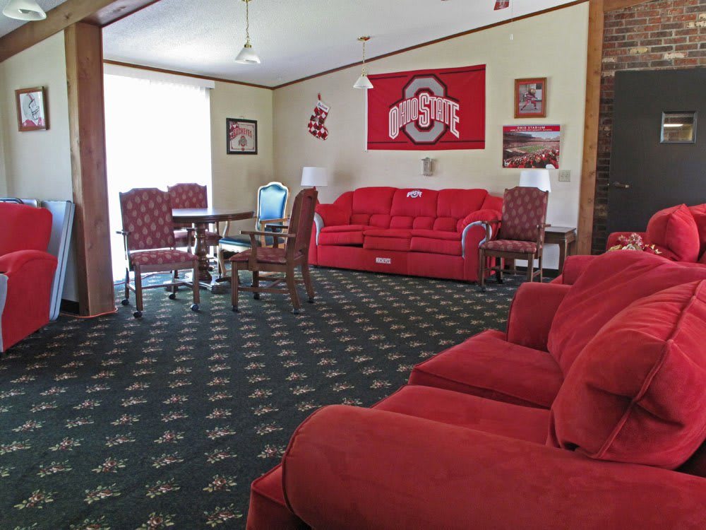 A cozy living room featuring Ohio State-themed decorations and red furniture.