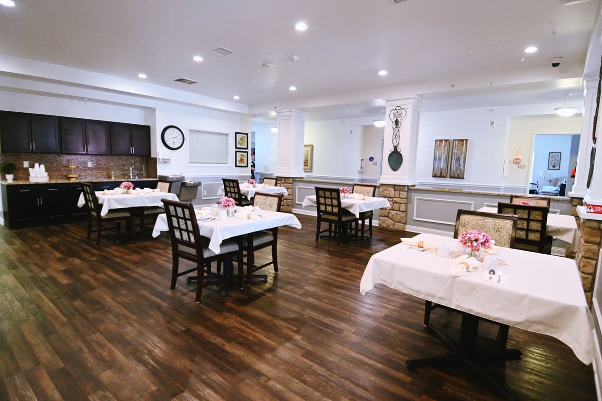 An elegant dining area with neatly arranged tables and chairs on a wooden floor.