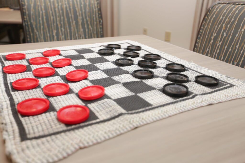 A checkers board set up on a table, featuring red and black pieces ready for play.