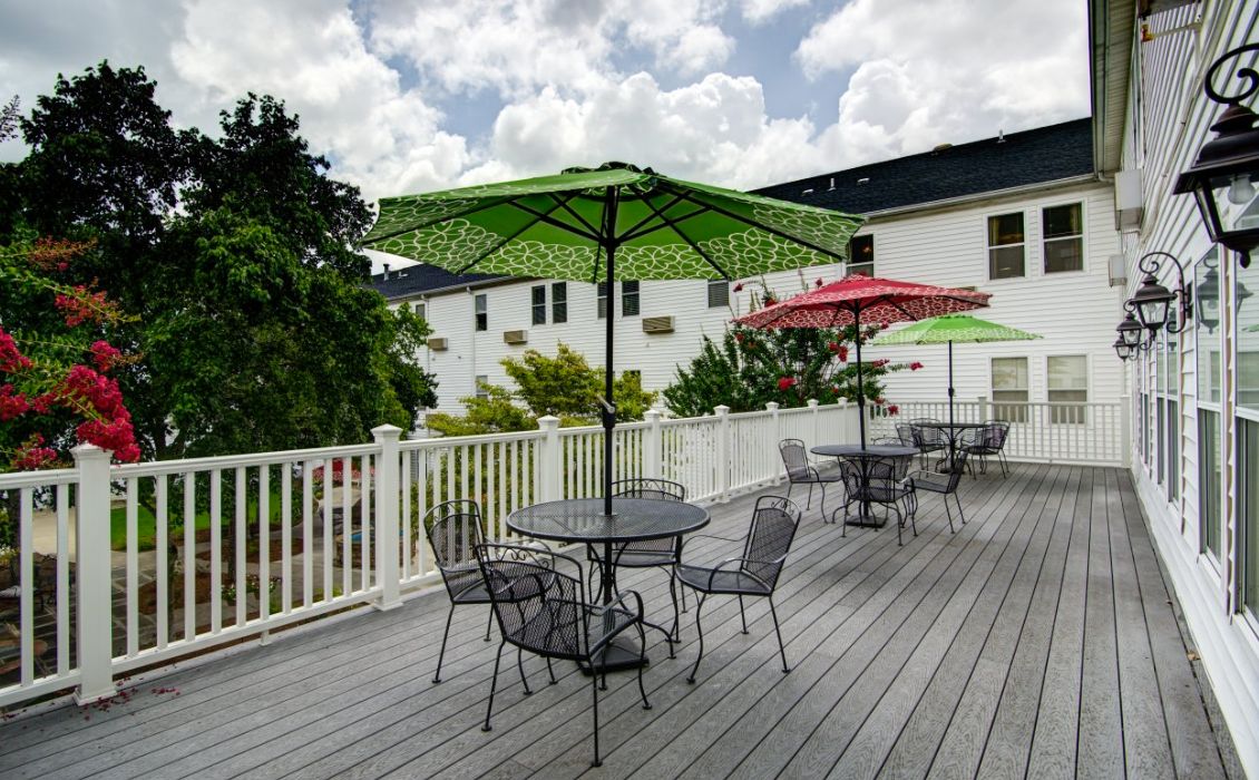 A spacious outdoor patio with tables and umbrellas on a deck under a cloudy sky.